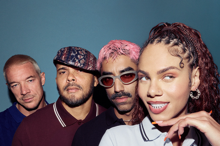 Promotional portrait of electronic dance music trio Major Lazer with Diplo, Walshy Fire, and Ape Drums posing against a teal blue background.